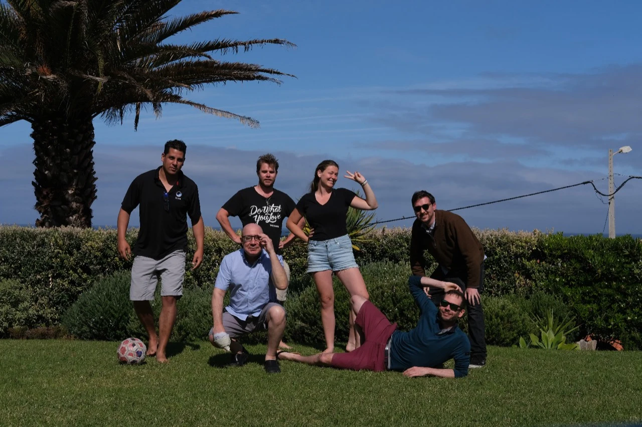 The Gybe team gathered outdoors beneath a palm tree